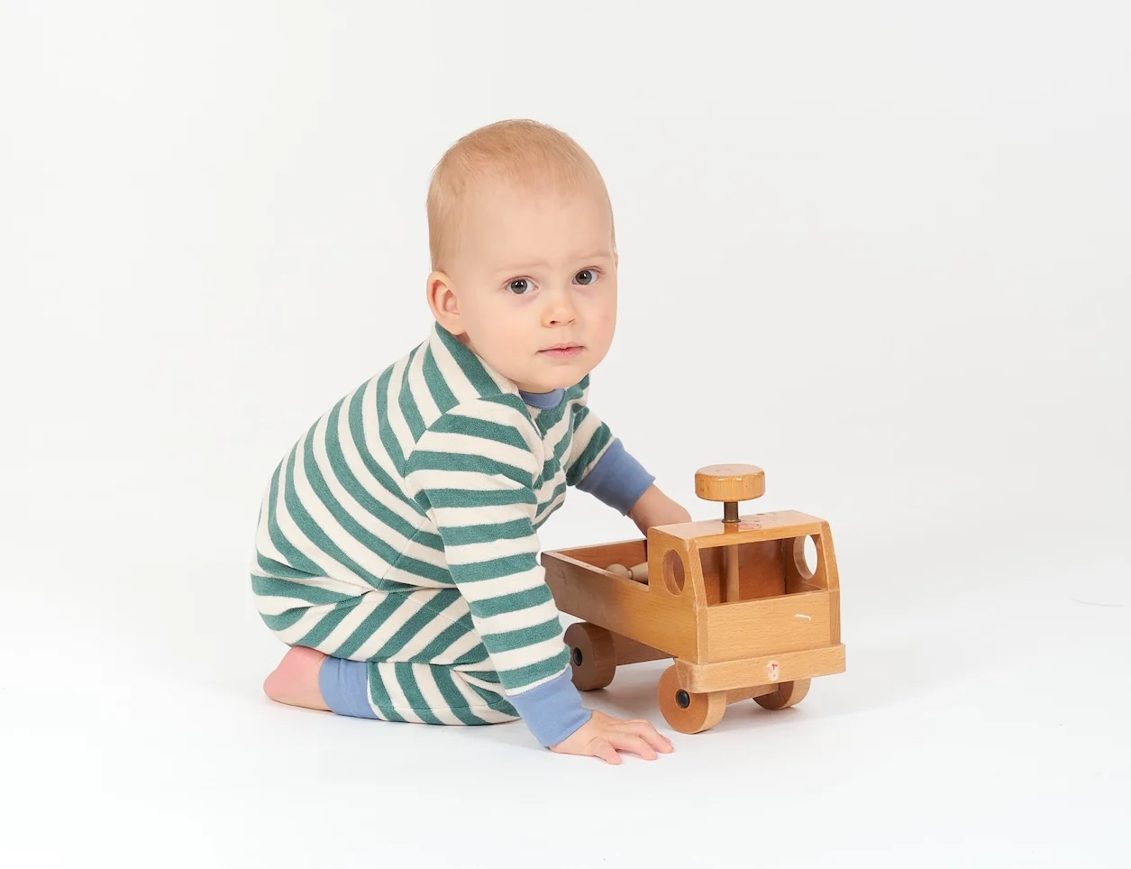 Baby im Strampler mit Spielzeug Unimog aus Holz