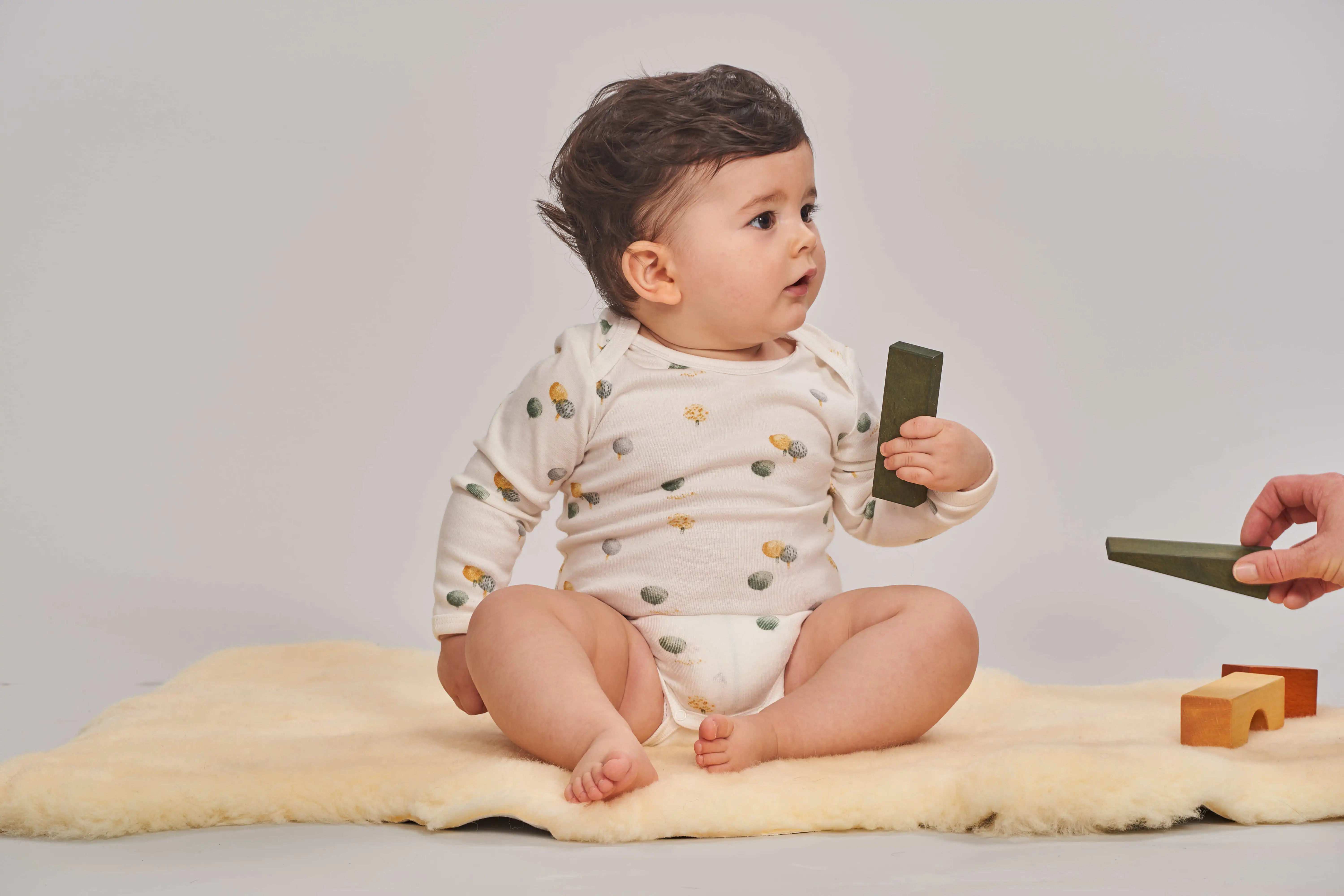 Baby sitzt auf dem Boden Baby mit Spielklötzen in der Hand
