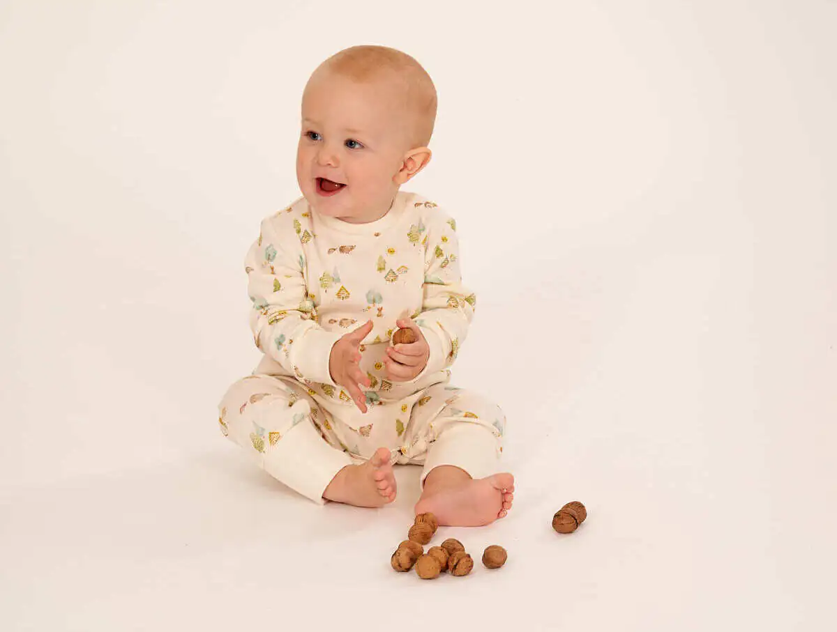 Baby im Strampler sitzt auf dem Boden