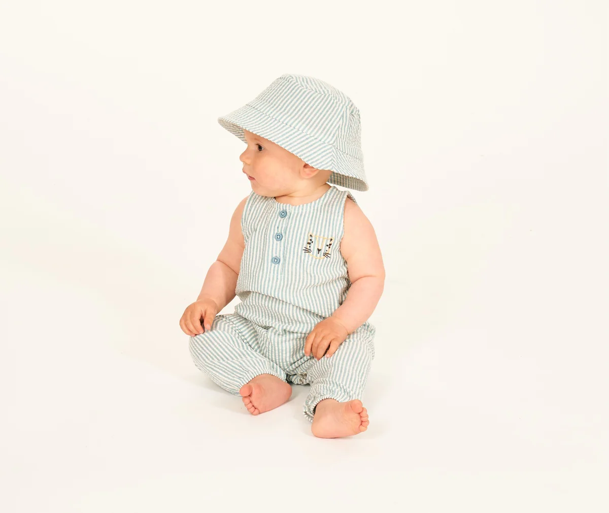 Baby sitzt im Sommeroutfit