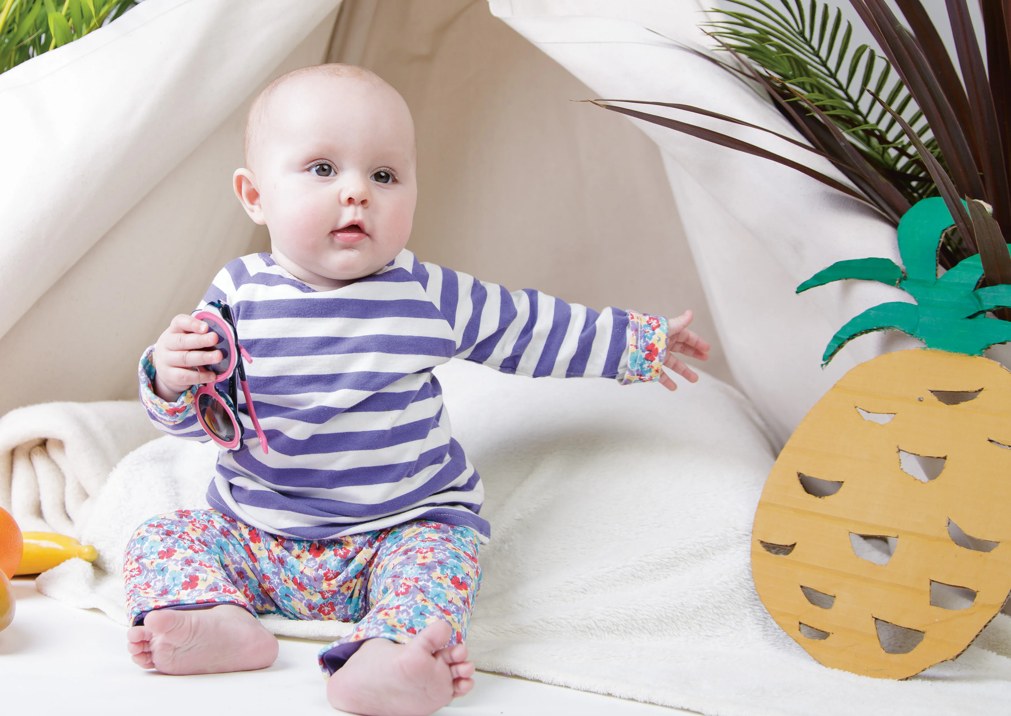 Baby mit Sonnenbrille in der Hand