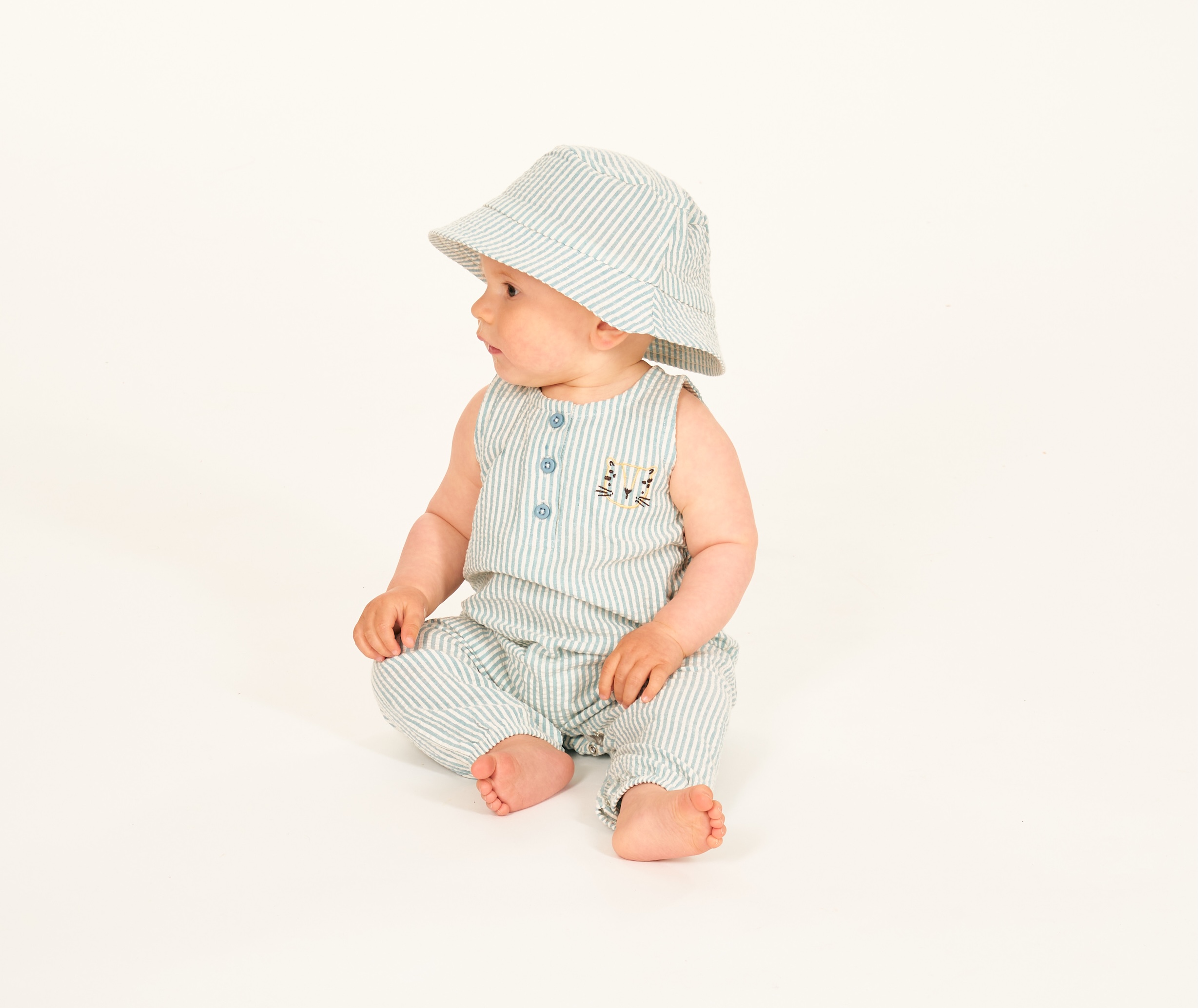Baby sitzt im Sommeroutfit