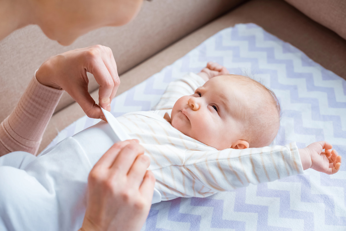 Frau hält Baby mit Strickjacke auf dem Arm