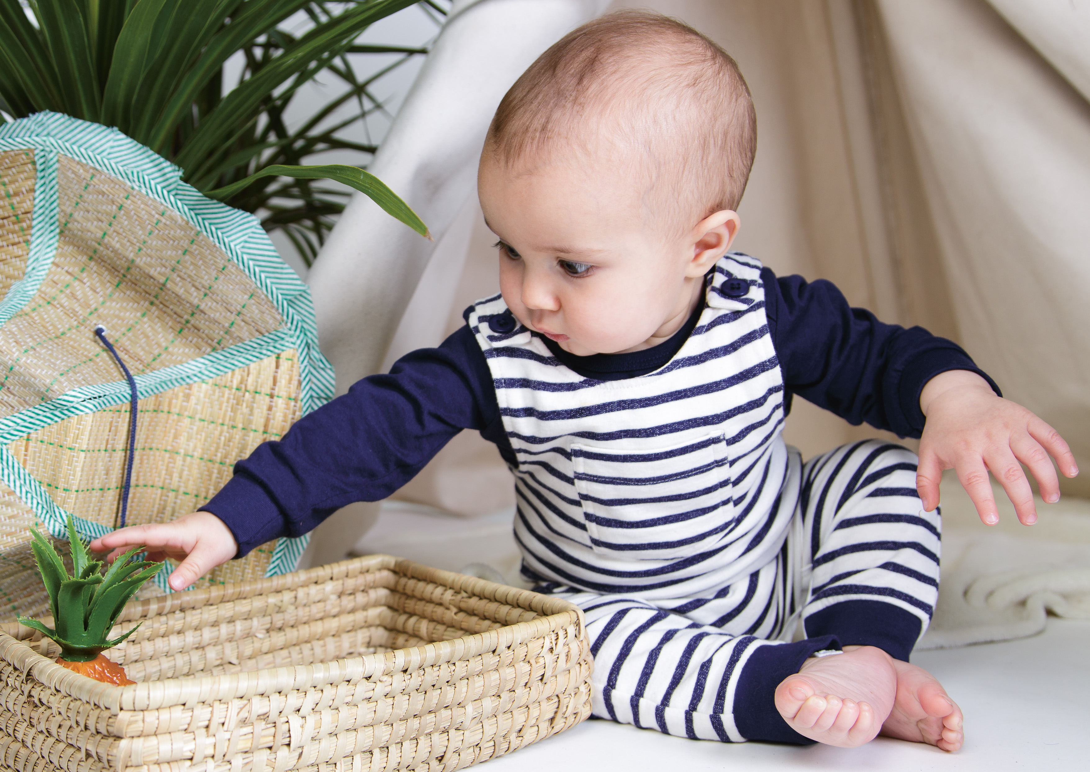 Baby greift nach einer Spielzeug-Ananas
