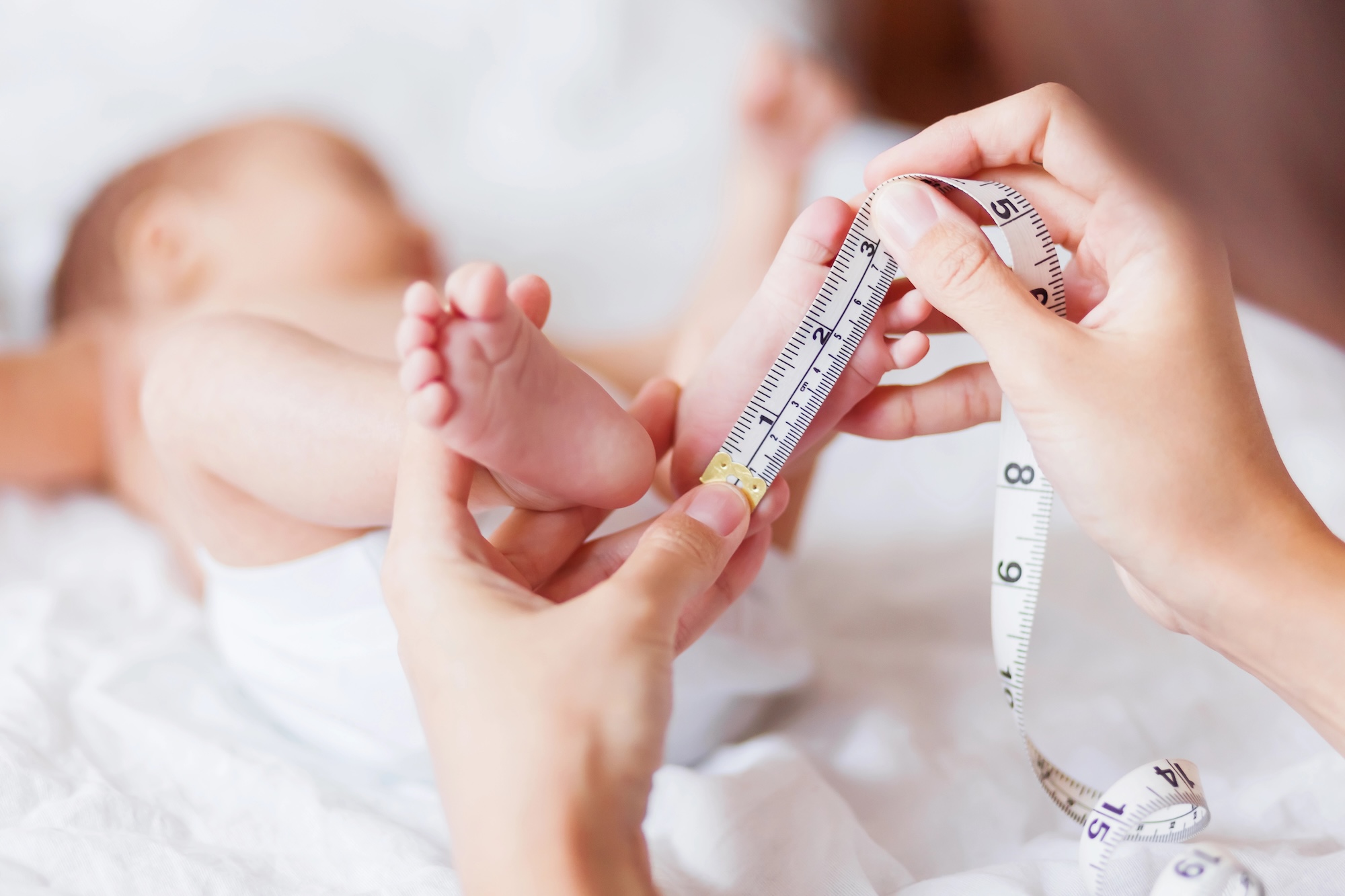 Babygröße: Mutter misst Babyfuß mit Maßband